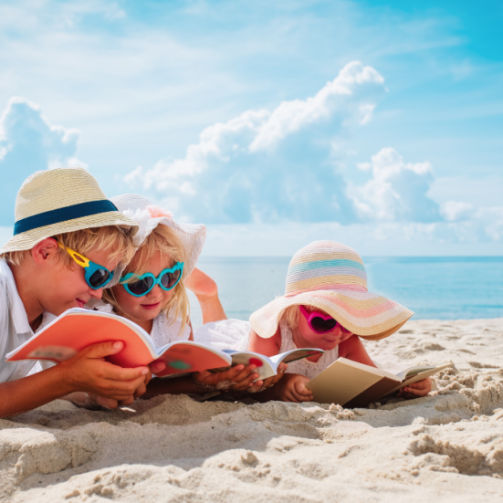 Børn læser sammen på stranden